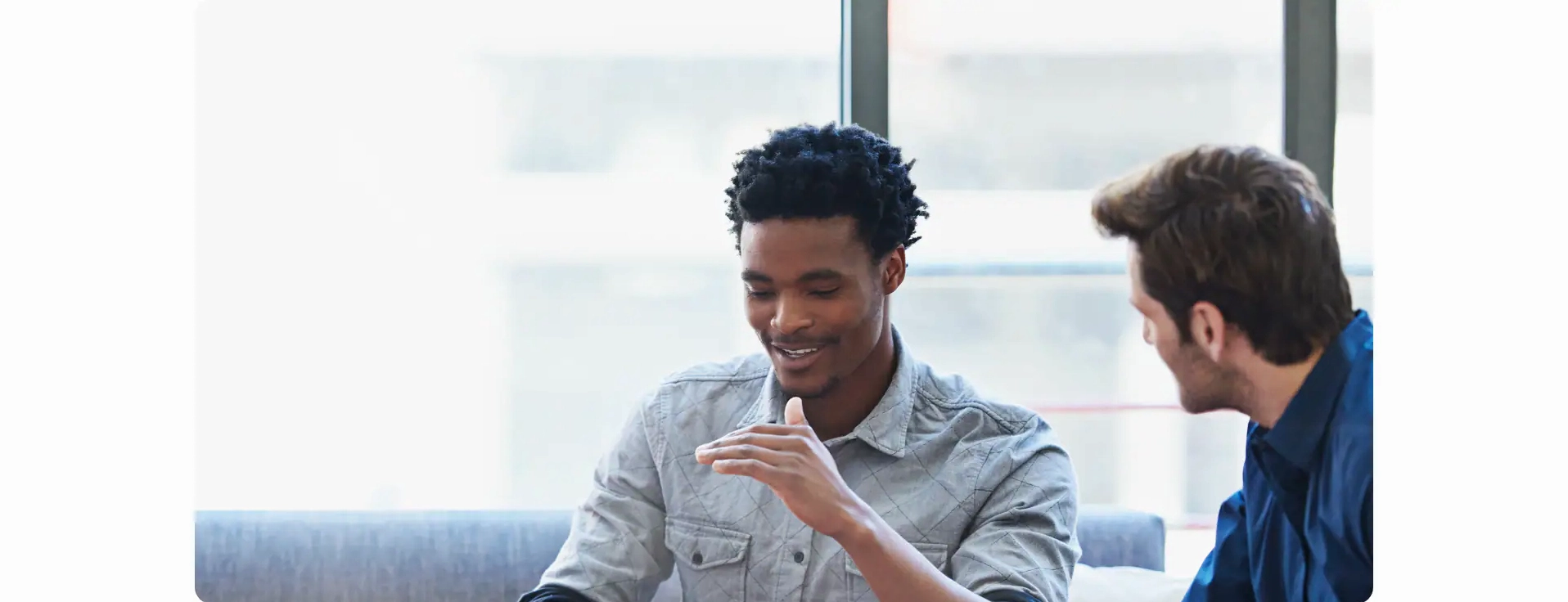 Hai nhân viên nam đang trò chuyện vui vẻ trên ghế sofa trong văn phòng Samsung